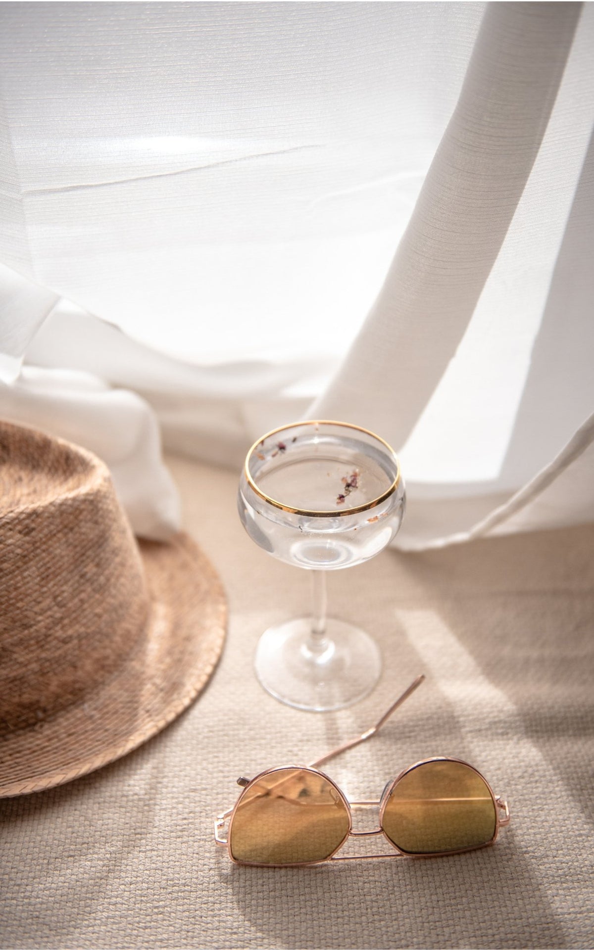 A stylish hat, sunglasses, and a glass of champagne elegantly arranged on a table, evoking a sense of leisure and celebration