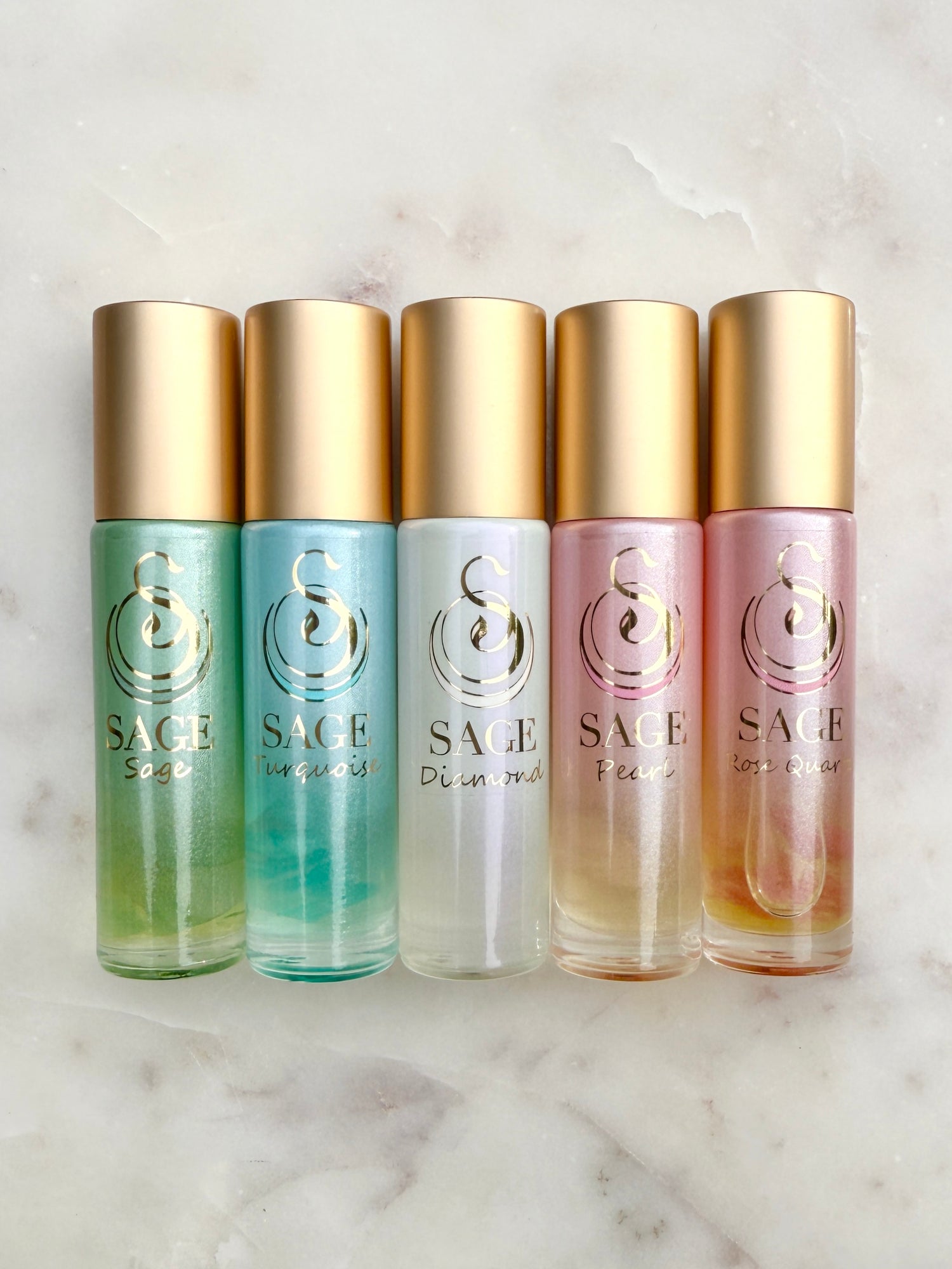 Five bottles of Sage perfume with gold caps on a marble surface