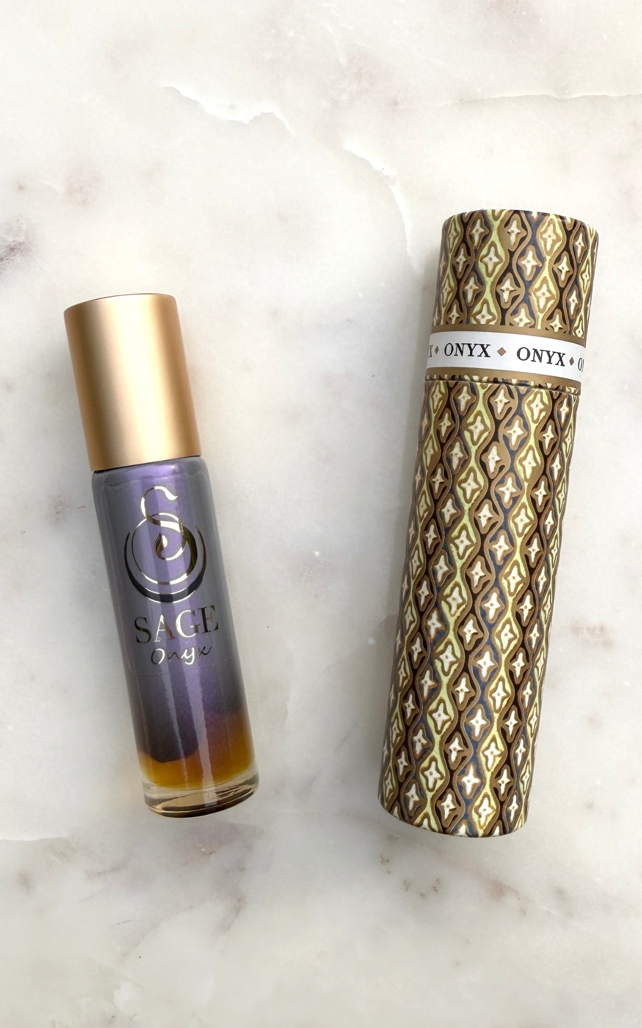 Onyx perfume roller bottle with gold cap and japanese washi paper box on a marble surface.