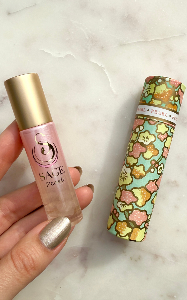 Perfume Roller Bottle with gold cap and pink body, Japanese washi paper box with floral design, on a marble surface
